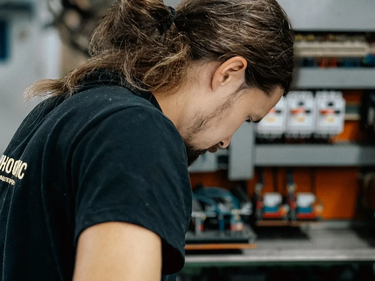 Técnico eléctrico trabajando concentrado frente a un tablero abierto