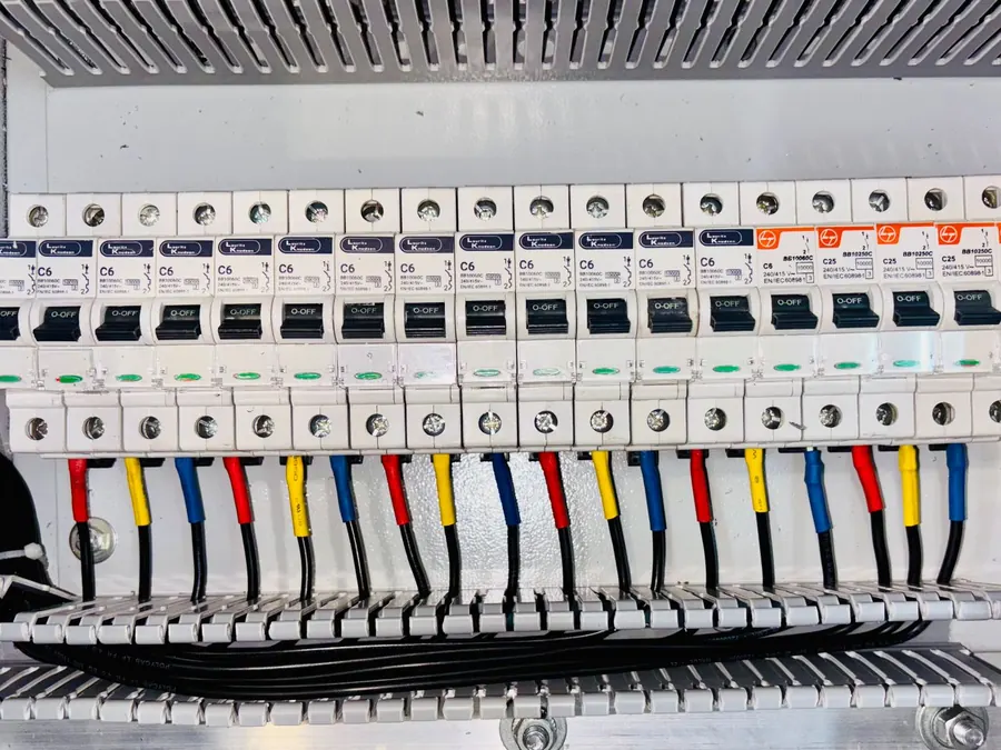 Tablero de distribución con interruptores alineados y conductores identificados por color