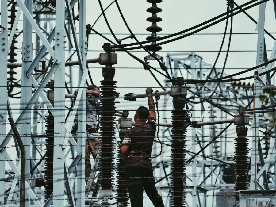 Personal trabajando en una subestación eléctrica entre aisladores y estructuras