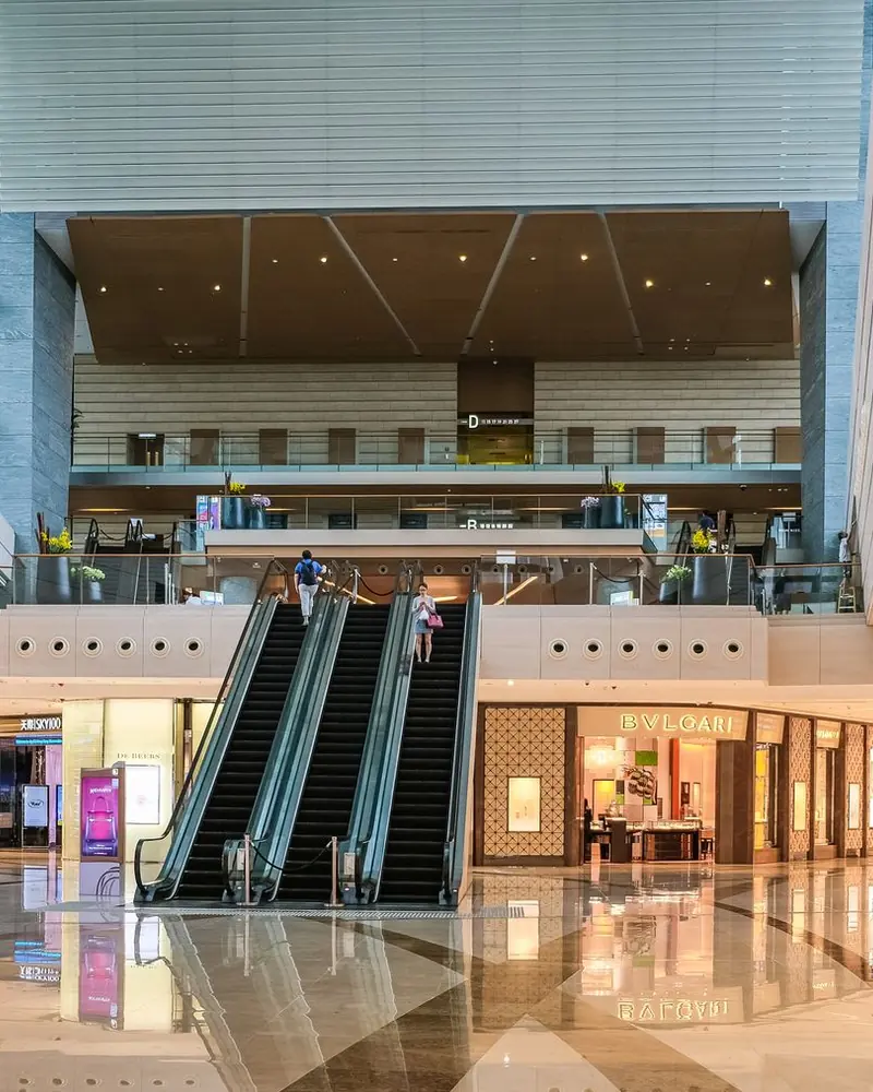 Interior de centro comercial con escaleras mecánicas y locales iluminados