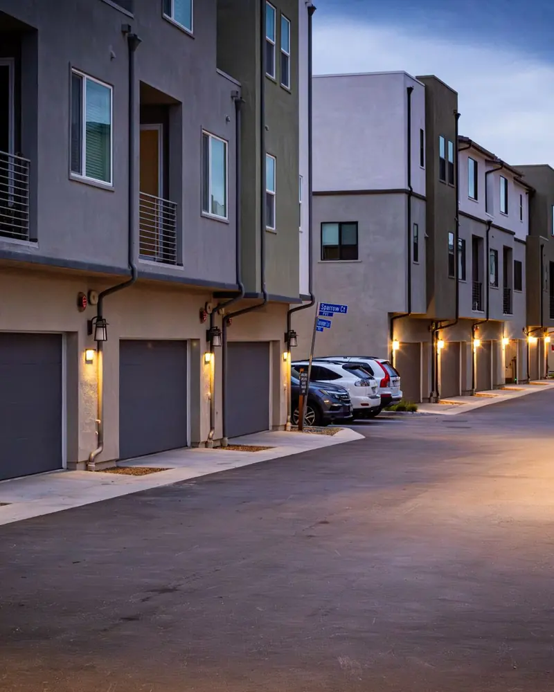 Calle interior de condominio con casas pareadas iluminadas al atardecer