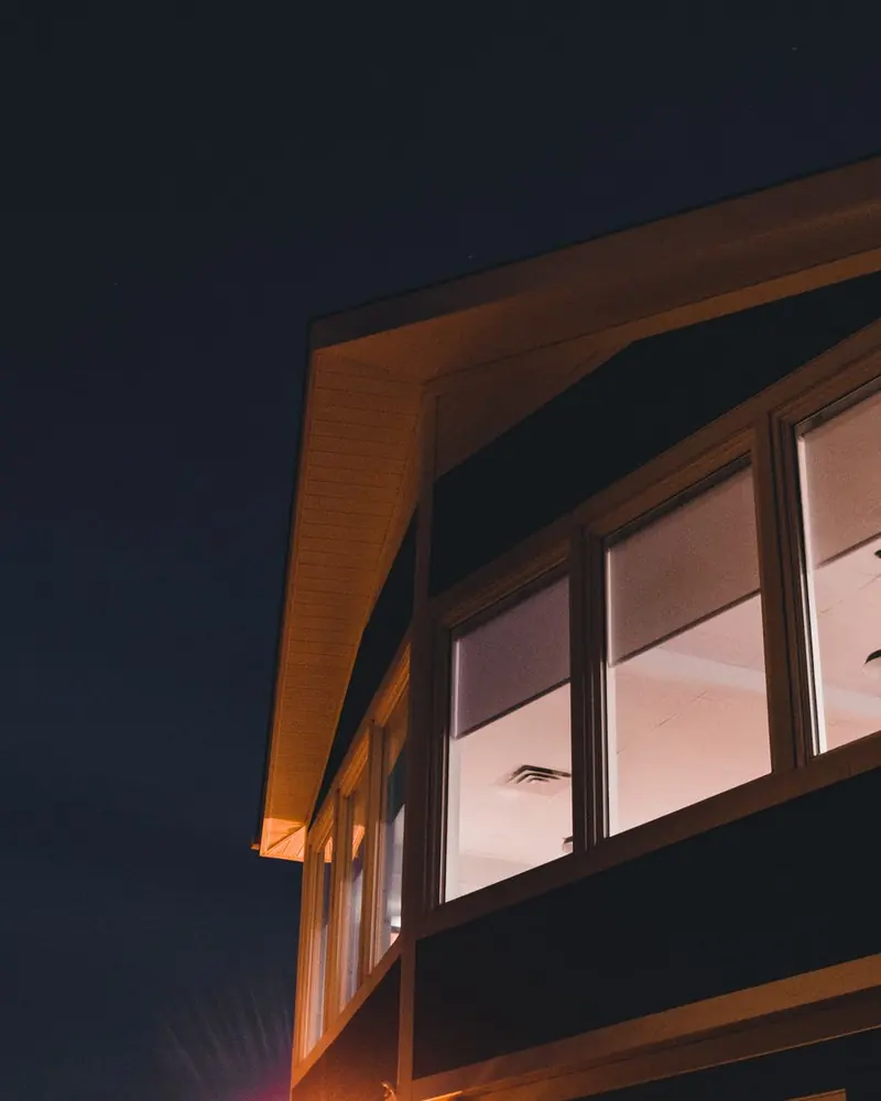 Vivienda con ventanales iluminados al anochecer